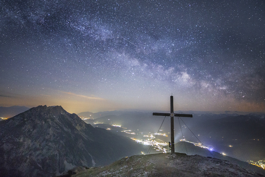 View of the Stoderzinken summit cross under the Milky Way and starry night sky with valley lights Liezen Steiermark Austria. View of the Stoderzinken summit cross under the Milky Way and starry night sky with valley lights Liezen Steiermark Austria.