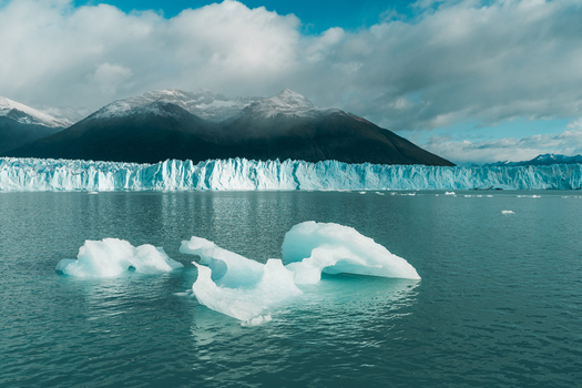 View of Perito Moreno Glacier with floating icebergs in the turquoise water framed by snow capped mountains under a cloudy sky in Perito Moreno Santa Cruz Province Argentina.