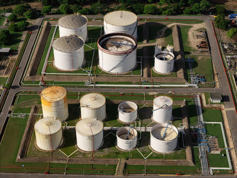 Aerial view of an industrial oil storage terminal featuring large white cylindrical storage tanks pipelines and containment berms in Bajos de Haina San Cristobal Provinc Dominican Republic.