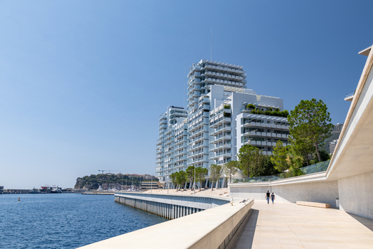 View of a modern white residential building with balconies along the waterfront promenade in Monaco City Monaco. View of a modern white residential building with balconies along the waterfront promenade in Monaco City Monaco.