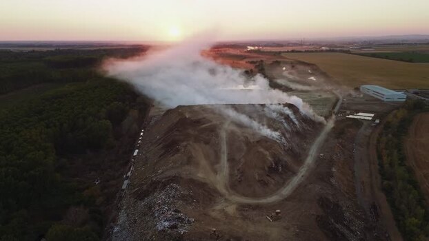 Aerial view of landfill with smoke at sunset in Sremska Mitrovica Serbia.