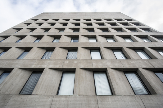 View of the modern concrete facade of a downtown building featuring a repetitive geometric window pattern under a cloudy sky in Lincoln Nebraska United States.