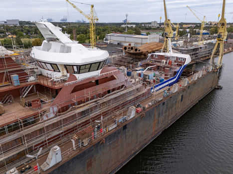 Aerial view of a ship under construction in a shipyard with scaffolding cranes and a white bridge structure in Gdansk Poland. Aerial view of a ship under construction in a shipyard with scaffolding cranes and a white bridge structure in Gdansk Poland.