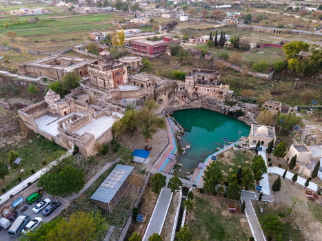 Aerial view of the historic Katas Raj Temple Complex featuring ancient stone structures a sacred emerald green pond and surrounding rural landscape in Katas Punjab Pakistan. Aerial view of the historic Katas Raj Temple Complex featuring ancient stone structures a sacred emerald green pond and surrounding rural landscape in Katas Punjab Pakistan.