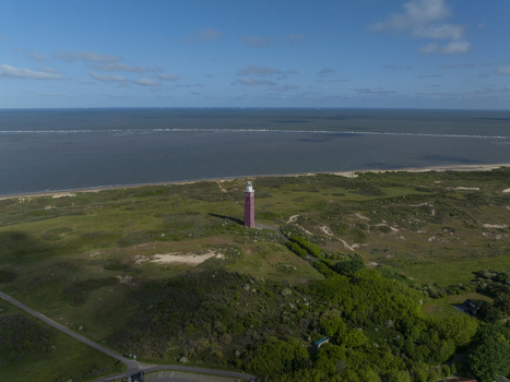 Aerial view of Westhoofd Lighthouse surrounded by sand dunes and green vegetation with the North Sea in the background in Ouddorp Zuid Holland Netherlands. Aerial view of Westhoofd Lighthouse surrounded by sand dunes and green vegetation with the North Sea in the background in Ouddorp Zuid Holland Netherlands.