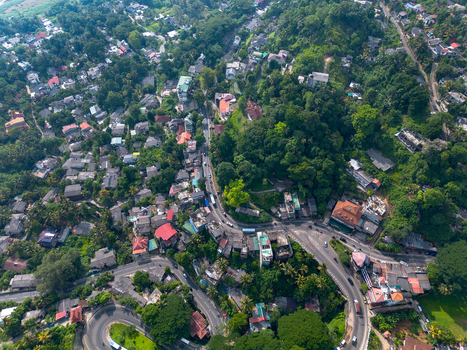Aerial view of Kandy Lake surrounded by dense tropical vegetation winding roads and residential buildings in Kandy Central Province Sri Lanka. Aerial view of Kandy Lake surrounded by dense tropical vegetation winding roads and residential buildings in Kandy Central Province Sri Lanka.
