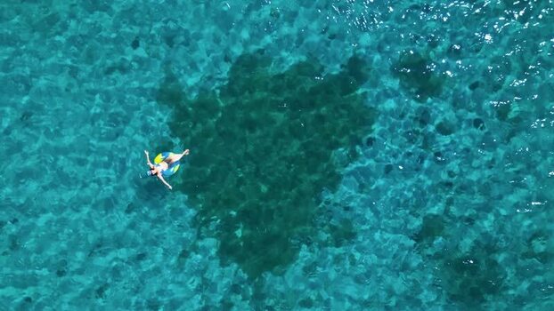 Aerial view of a person floating in turquoise water in Guanaja Honduras. Aerial view of a person floating in turquoise water in Guanaja Honduras.
