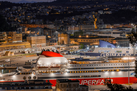 Aerial view of Ancona Port at night with a large ferry docked at the pier illuminated city buildings and harbor infrastructure in Ancona Marche Italy. Aerial view of Ancona Port at night with a large ferry docked at the pier illuminated city buildings and harbor infrastructure in Ancona Marche Italy.