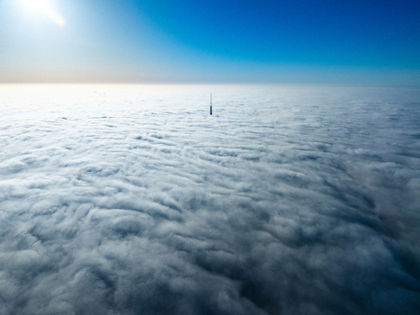 Aerial view of the Riga Radio and TV Tower rising above a thick blanket of clouds under a clear blue sky in Riga Latvia. Aerial view of the Riga Radio and TV Tower rising above a thick blanket of clouds under a clear blue sky in Riga Latvia.