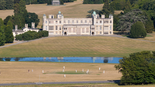 Aerial view of Audley End House with a cricket match being played on the lawn in the foreground surrounded by expansive parkland and trees in Audley End England United Kingdom. Aerial view of Audley End House with a cricket match being played on the lawn in the foreground surrounded by expansive parkland and trees in Audley End England United Kingdom.