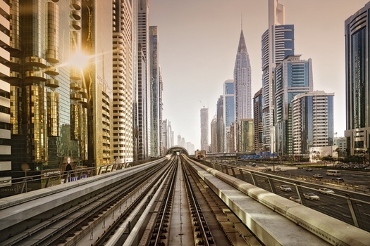 Dubai United Arab Emirates 21 April 2023 View of the Dubai Metro tracks running through the modern skyline with glass skyscrapers and golden hour sunlight. Dubai United Arab Emirates 21 April 2023 View of the Dubai Metro tracks running through the modern skyline with glass skyscrapers and golden hour sunlight.
