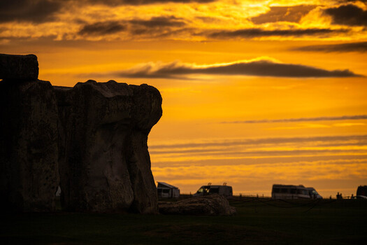 View of the silhouette of Stonehenge megalithic stones against a vibrant orange sunset sky in Salisbury England United Kingdom.