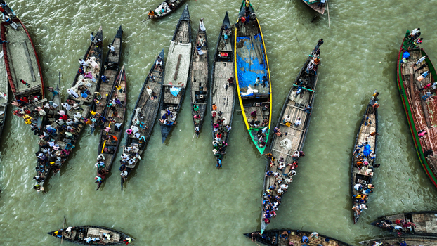 Baghabari Bangladesh 20 August 2022 Aerial view of numerous wooden boats crowded with people navigating the river with some vessels covered by blue tarps in the Rajshahi Division.