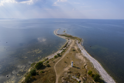 Aerial view of the Neeme lighthouse situated on a narrow rocky peninsula extending into the Baltic Sea surrounded by coastal vegetation and calm waters in Neeme Harju County Estonia.