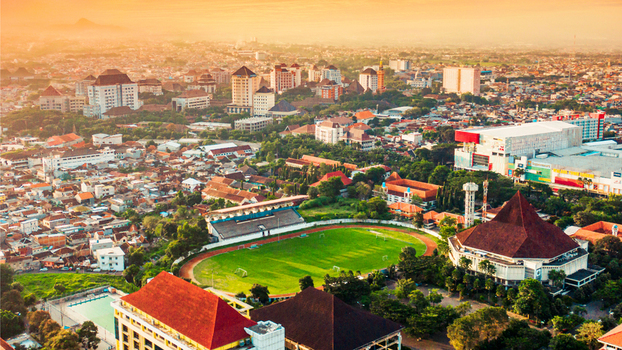 Aerial view of Cakrawala Stadium surrounded by urban buildings lush trees and a vibrant cityscape under a warm golden hour sky in Kecamatan Lowokwaru Jawa Timur Indonesia. Aerial view of Cakrawala Stadium surrounded by urban buildings lush trees and a vibrant cityscape under a warm golden hour sky in Kecamatan Lowokwaru Jawa Timur Indonesia.