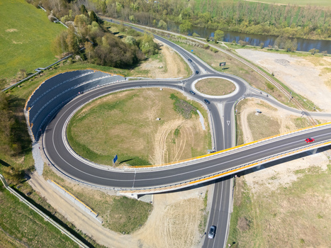 Aerial view of a modern road roundabout and bridge overpass surrounded by lush green fields and a winding river in Nizna Zilina Region Slovakia. Aerial view of a modern road roundabout and bridge overpass surrounded by lush green fields and a winding river in Nizna Zilina Region Slovakia.