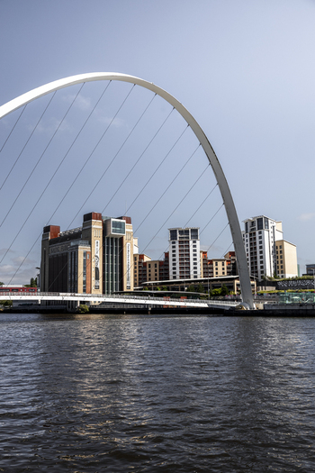 View of the Millennium Bridge spanning the River Tyne with the Baltic Centre for Contemporary Art and modern buildings in the background in Newcastle upon Tyne England United Kingdom. View of the Millennium Bridge spanning the River Tyne with the Baltic Centre for Contemporary Art and modern buildings in the background in Newcastle upon Tyne England United Kingdom.