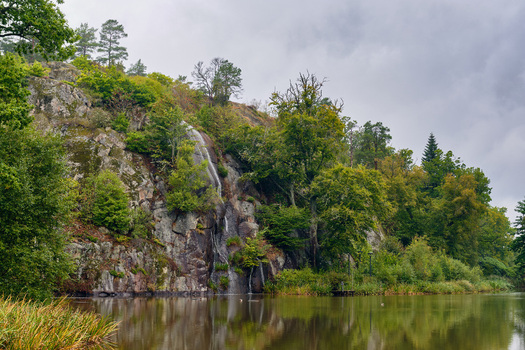Ronneby Blekinge County Sweden 11 September 2025 View of a small waterfall cascading down a rocky cliff face surrounded by lush green trees and foliage in Brunssparken. Ronneby Blekinge County Sweden 11 September 2025 View of a small waterfall cascading down a rocky cliff face surrounded by lush green trees and foliage in Brunssparken.