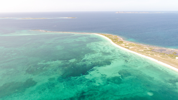 Aerial view of the Los Roques archipelago featuring turquoise waters a white sand beach and coastal vegetation in Los Roques Dependencias Federales Venezuela. Aerial view of the Los Roques archipelago featuring turquoise waters a white sand beach and coastal vegetation in Los Roques Dependencias Federales Venezuela.