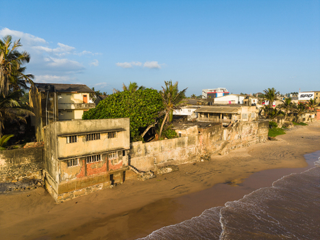 Aerial view of weathered coastal buildings and palm trees along a sandy beach under a clear blue sky Galle Southern Province Sri Lanka.