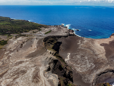 Aerial view of the stark volcanic landscape meets the vast deep blue Atlantic ocean a contrast of raw earth and boundless sea Capelo A&ccedil;ores Portugal.
