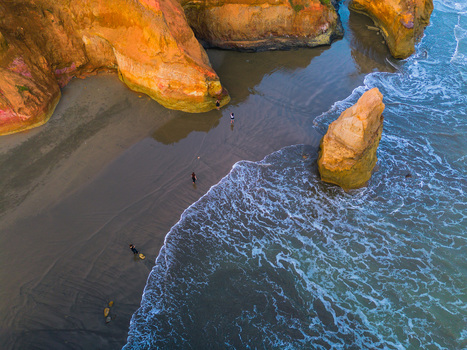 Aerial view of sandy beach with rock formations ocean waves and people walking on the shore in Bali Bali Indonesia. Aerial view of sandy beach with rock formations ocean waves and people walking on the shore in Bali Bali Indonesia.