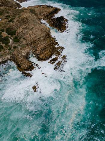 Aerial view of Injidup Natural Spa with turquoise waves crashing against rugged rocky cliffs and white sea foam along the coastline in Yallingup Western Australia Australia. Aerial view of Injidup Natural Spa with turquoise waves crashing against rugged rocky cliffs and white sea foam along the coastline in Yallingup Western Australia Australia.
