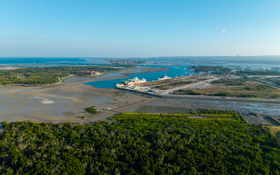 Aerial view of an FSRU ship docked in the coastal waters near mangroves and mudflats in Kecamatan Denpasar Selatan Bali Indonesia.