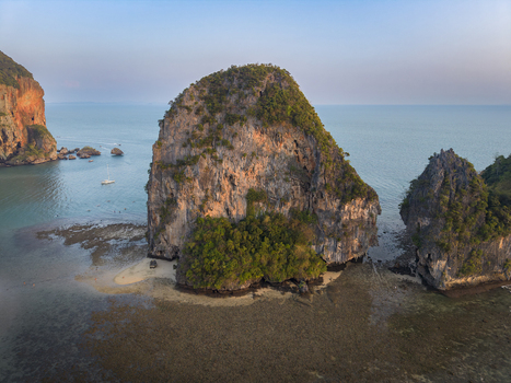 Aerial view of dramatic limestone karsts rise majestically from the turquoise waters fringed by sandy shores creating a stunning contrast of textures Krabi Thailand.