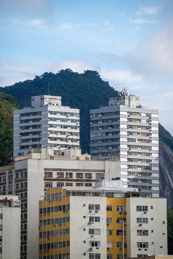 View of modern residential buildings in the Botafogo neighborhood with lush green hills and a cloudy sky in the background Rio de Janeiro State of Rio de Janeiro Brazil. View of modern residential buildings in the Botafogo neighborhood with lush green hills and a cloudy sky in the background Rio de Janeiro State of Rio de Janeiro Brazil.