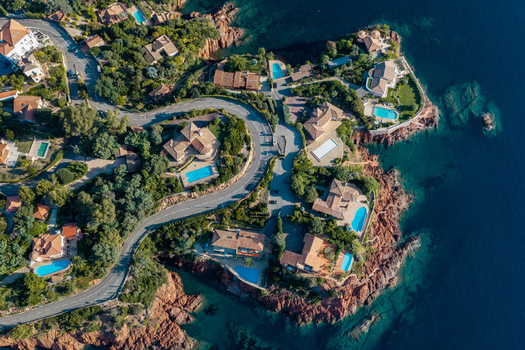 Aerial view of Le Trayas villas with pools nestled among lush greenery and red rock cliffs overlooking the Mediterranean Sea Saint Raphael Provence Alpes Cote d Azur France. Aerial view of Le Trayas villas with pools nestled among lush greenery and red rock cliffs overlooking the Mediterranean Sea Saint Raphael Provence Alpes Cote d Azur France.