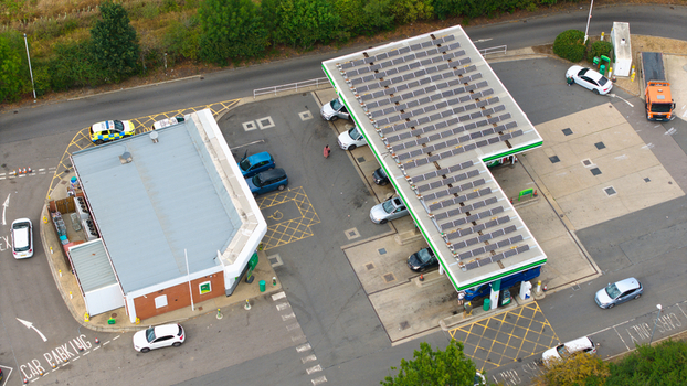 Aerial view of a gas station with solar panels installed on the roof featuring parked cars and a police vehicle in the parking lot Bedford England United Kingdom.