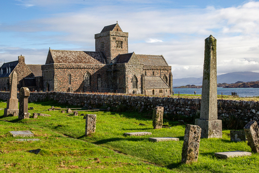 View of Iona Abbey and Nunnery with ancient stone crosses in the graveyard and the sea in the background Isle of Iona Scotland United Kingdom. View of Iona Abbey and Nunnery with ancient stone crosses in the graveyard and the sea in the background Isle of Iona Scotland United Kingdom.