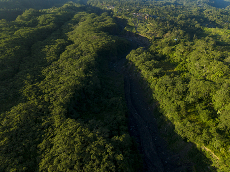 Aerial view of the lush tropical forest and deep volcanic ravine near Bunker Kaliadem Merapi under morning sunlight in Kecamatan Pakem Daerah Istimewa Yogya Indonesia. Aerial view of the lush tropical forest and deep volcanic ravine near Bunker Kaliadem Merapi under morning sunlight in Kecamatan Pakem Daerah Istimewa Yogya Indonesia.
