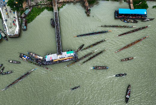 Baghabari Rajshahi Division Bangladesh 20 August 2022 Aerial view of traditional long racing boats navigating the river near the Baghabari pier with many people gathered on the dock and in the vessels.