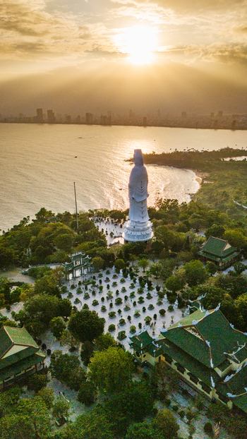 Aerial view of the Lady Buddha statue at Linh Ung Pagoda surrounded by lush gardens and traditional temple architecture overlooking the coastline of Da Nang Vietnam. Aerial view of the Lady Buddha statue at Linh Ung Pagoda surrounded by lush gardens and traditional temple architecture overlooking the coastline of Da Nang Vietnam.
