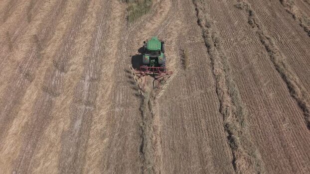 Aerial view of green tractor raking hay in South Africa. Aerial view of green tractor raking hay in South Africa.