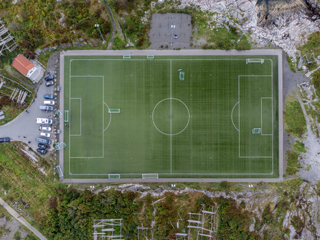 Aerial view of a vibrant green football field nestled between rocky outcrops and sparse vegetation a stark contrast of man made order against nature s ruggedness Henningsvær Norway. Aerial view of a vibrant green football field nestled between rocky outcrops and sparse vegetation a stark contrast of man made order against nature s ruggedness Henningsvær Norway.
