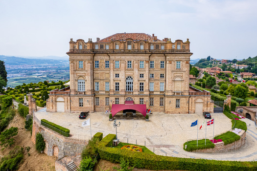 Aerial view of the historic Castello di Guarene with its grand Baroque facade manicured gardens and people near the entrance Guarene Piedmont Italy. Aerial view of the historic Castello di Guarene with its grand Baroque facade manicured gardens and people near the entrance Guarene Piedmont Italy.