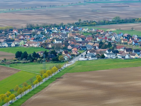Aerial view of a quaint village nestled amid a patchwork of brown fields and green meadows a tranquil scene of rural life Neuf Brisach Grand Est France.