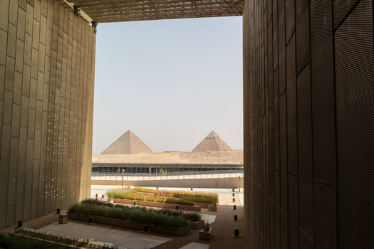 Giza Egypt 16 May 2026 View of the Grand Egyptian Museum looking towards the Great Pyramids of Giza through a large architectural opening under a clear sky.