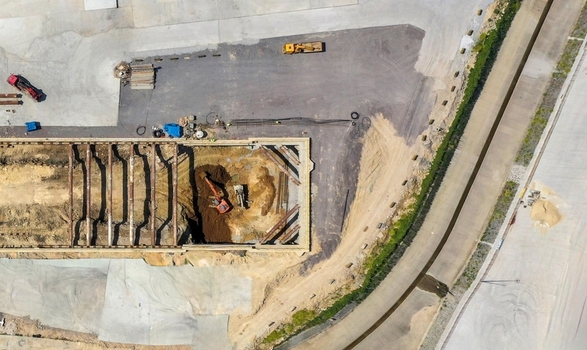 Aerial view of an active construction site with an excavator digging in a foundation pit near steel reinforcements and heavy machinery in Avcilar Istanbul Turkey. Aerial view of an active construction site with an excavator digging in a foundation pit near steel reinforcements and heavy machinery in Avcilar Istanbul Turkey.