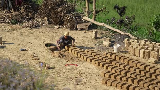 View of a man making handmade mud bricks in a rural field Nepal.