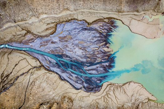 Aerial view of a glacial river delta with intricate blue meltwater channels flowing into a turquoise lake surrounded by sediment rich riverbanks in Prutz Tyrol Austria. Aerial view of a glacial river delta with intricate blue meltwater channels flowing into a turquoise lake surrounded by sediment rich riverbanks in Prutz Tyrol Austria.
