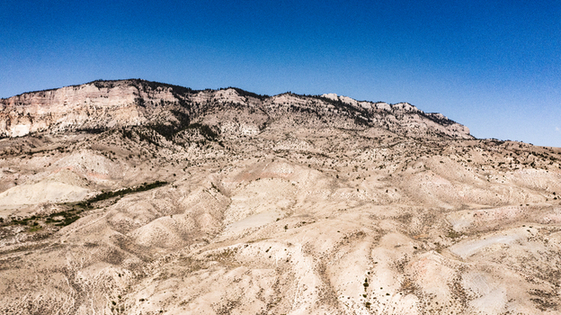 Aerial view of the rugged arid landscape and rocky mountain ridges under a clear blue sky in Cody Wyoming United States.