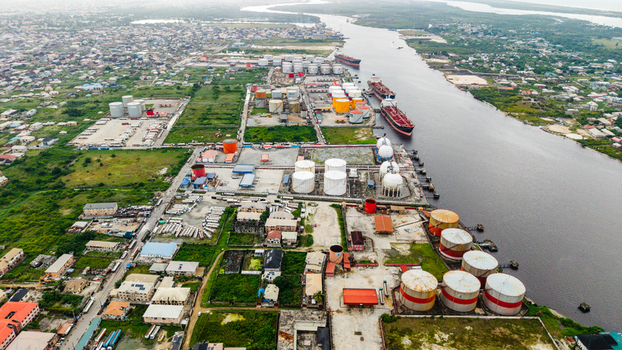 Aerial view of the industrial storage facility in Satellite Town featuring large fuel storage tanks cargo ships docked along the river and urban infrastructure in Lagos Lagos Nigeria.