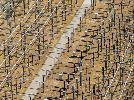 Aerial view of the Amprion Umspannwerk electrical substation featuring complex metal structures power lines and insulators set against dry grassy ground Pfungstadt Hessen Germany.