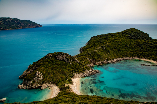 Aerial view of the double bay of Porto Timoni with turquoise waters lush green hills and rocky coastline Corfu Ionian Islands Greece. Aerial view of the double bay of Porto Timoni with turquoise waters lush green hills and rocky coastline Corfu Ionian Islands Greece.