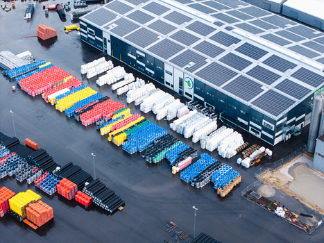 Jelgava Latvia 04 July 2026 Aerial view of an industrial facility featuring rows of colorful plastic pipes in the yard and solar panels installed on the large warehouse roof.
