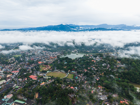 Aerial view of the urban landscape featuring Bogambara Stadium and Kandy Lake surrounded by lush green hills and misty mountains Kandy Central Province Sri Lanka. Aerial view of the urban landscape featuring Bogambara Stadium and Kandy Lake surrounded by lush green hills and misty mountains Kandy Central Province Sri Lanka.